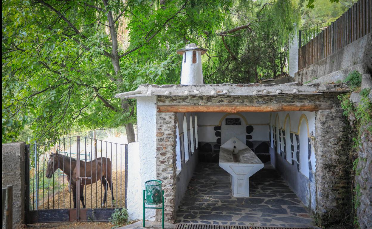 El lavadero de Busquístar y la pequeña finca aledaña, en la que hay un caballo. 