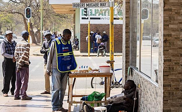 Un hombre charla con un joven que vende huevos en la calle principal de Bulawayo, bautizada con el nombre del omnipresente dictador.