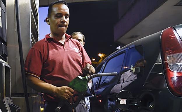 Un hombre reposta combustible en una estación de servicio.