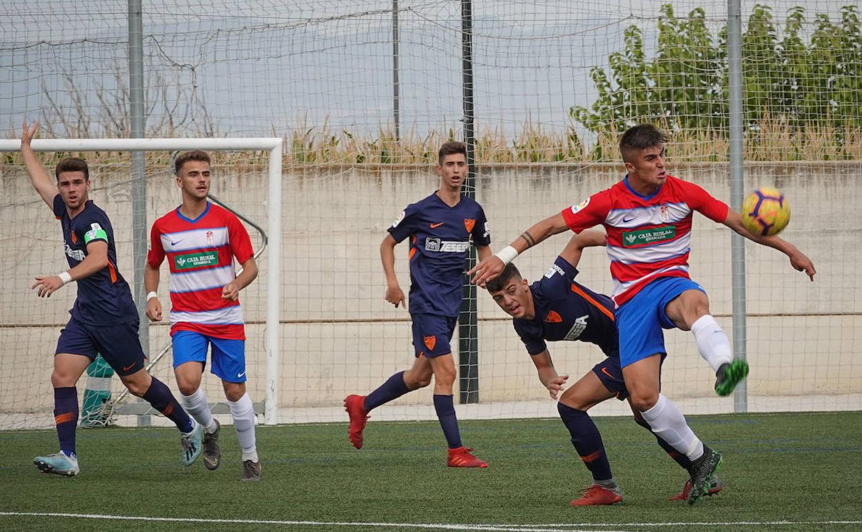 David Santisteban, referencia goleadora del Granada, controla el balón ante la entrada de un rival malaguista. 