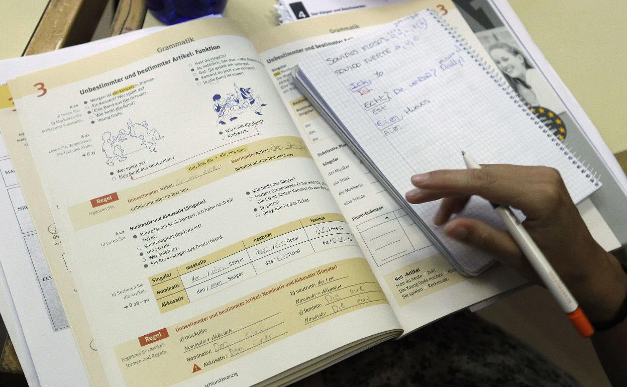 Un estudiante coge apuntos de un libro. 