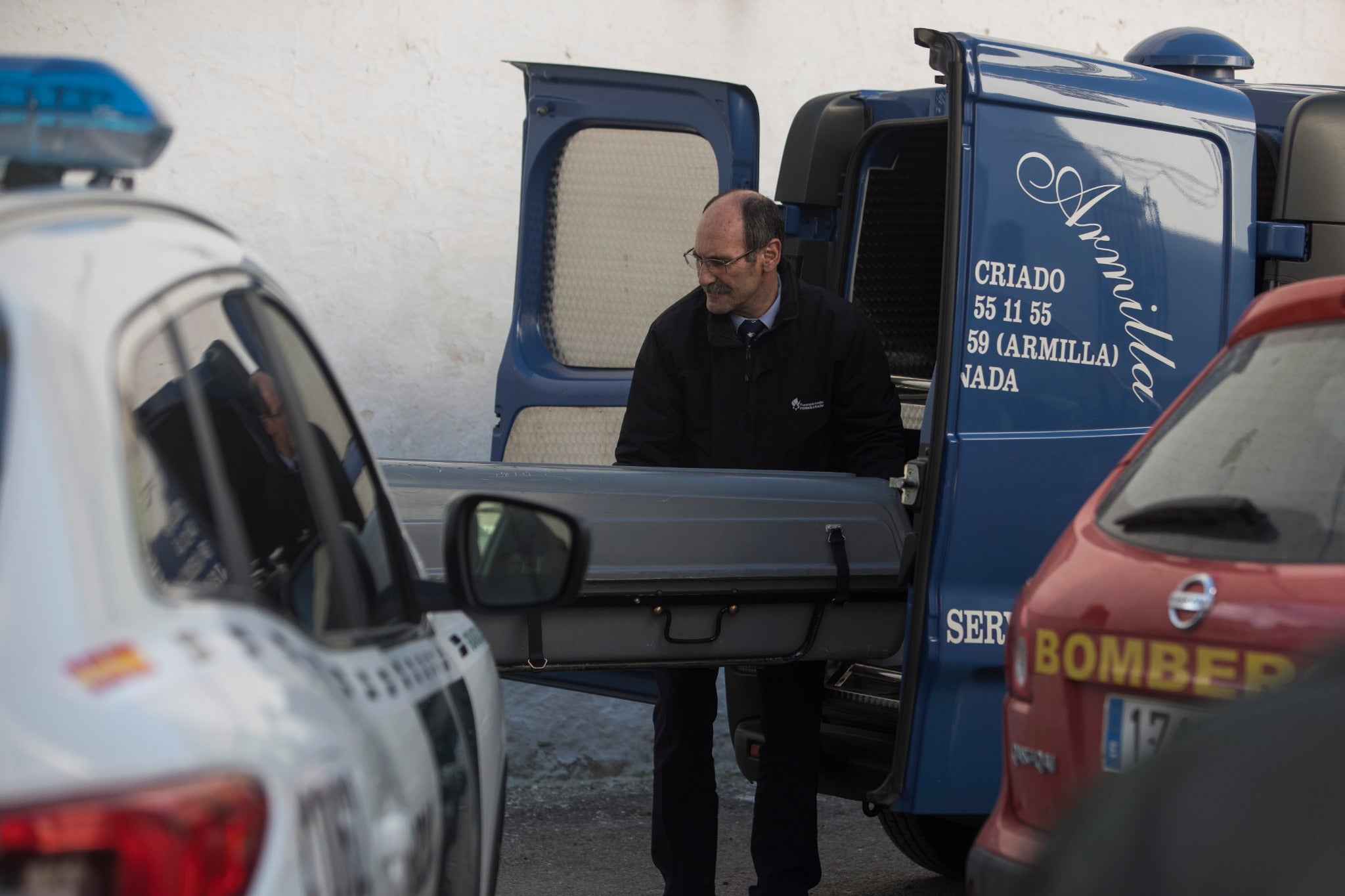 Miembros de la funeraria proceden a guardar uno de los féretros en el vehículo.