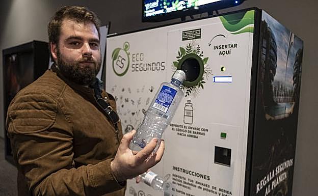Un cliente sostiene una botella antes de reciclarla en la máquina de 'Segundos para el planeta' situada en el Kinépolis del Nevada
