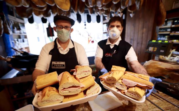 Los dos charcuteros que están donando el embutido y preparando los bocadillos.