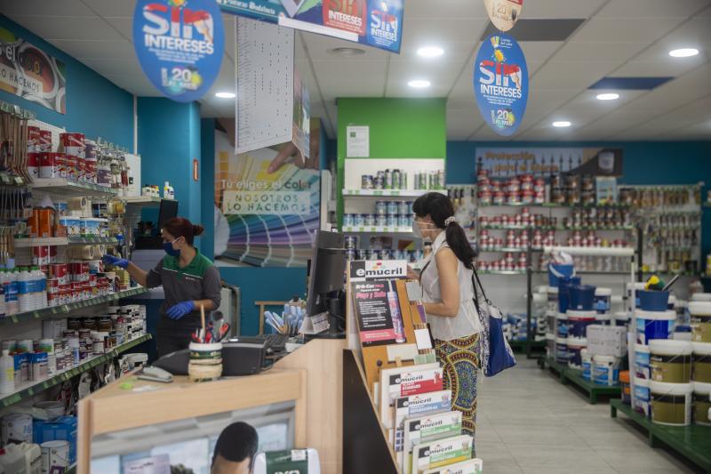 Una trabajadora de una tienda de pinturas de Sevillla atiende a una clienta durante el primer día de apertura con limitaciones de este tipo de comercio desde que se decretó el estado de alarma en España.