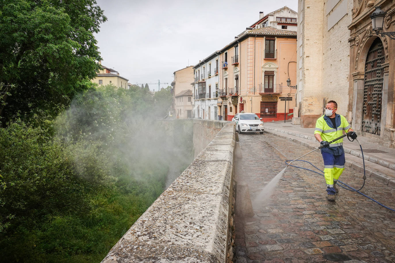 Operarios de Inagra desinfectan el Paseo de los Tristes, con la Alhambra como telón de fondo.