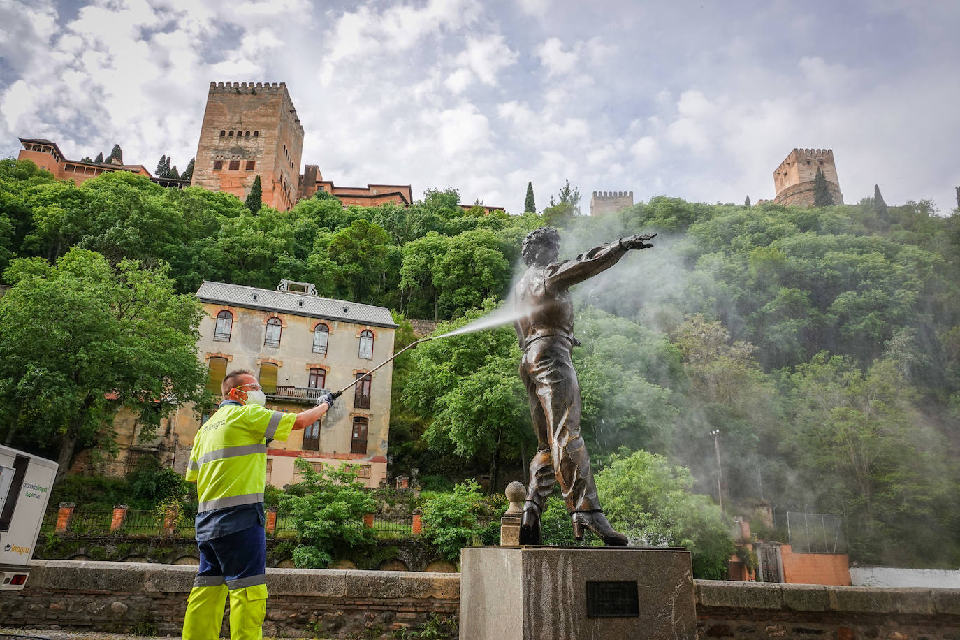 Operarios de Inagra desinfectan el Paseo de los Tristes, con la Alhambra como telón de fondo.