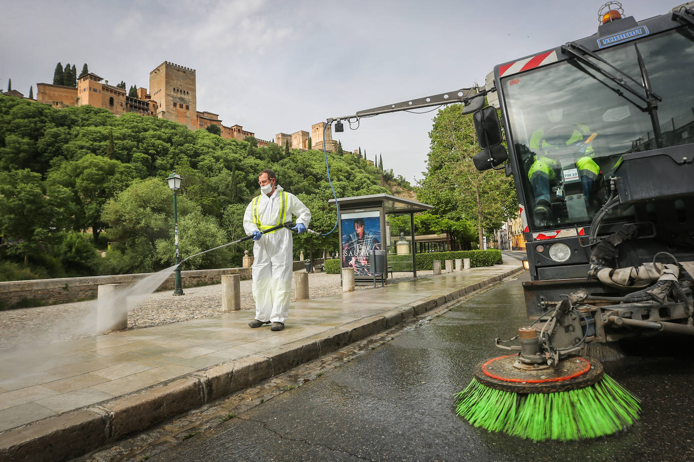Operarios de Inagra desinfectan el Paseo de los Tristes, con la Alhambra como telón de fondo.