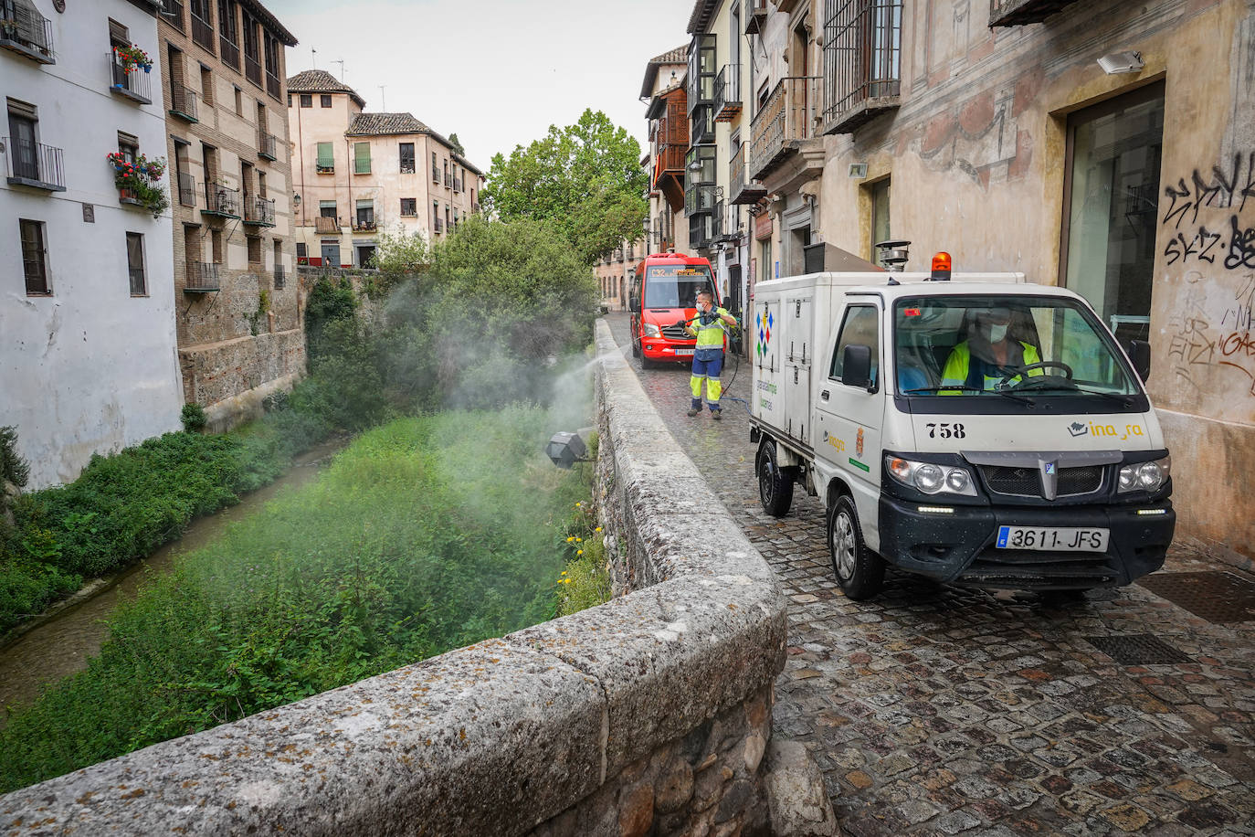Operarios de Inagra desinfectan el Paseo de los Tristes, con la Alhambra como telón de fondo.