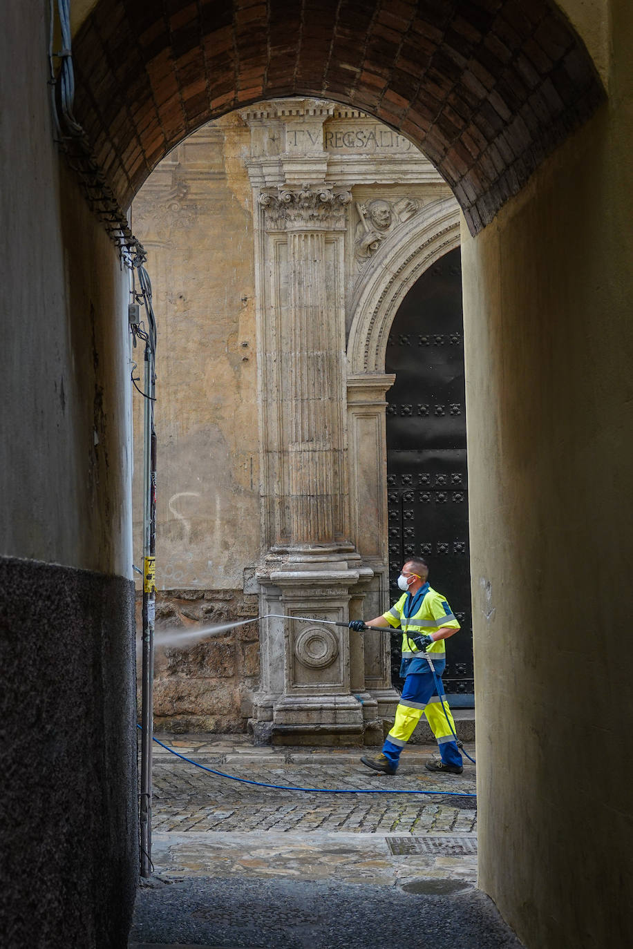 Operarios de Inagra desinfectan el Paseo de los Tristes, con la Alhambra como telón de fondo.