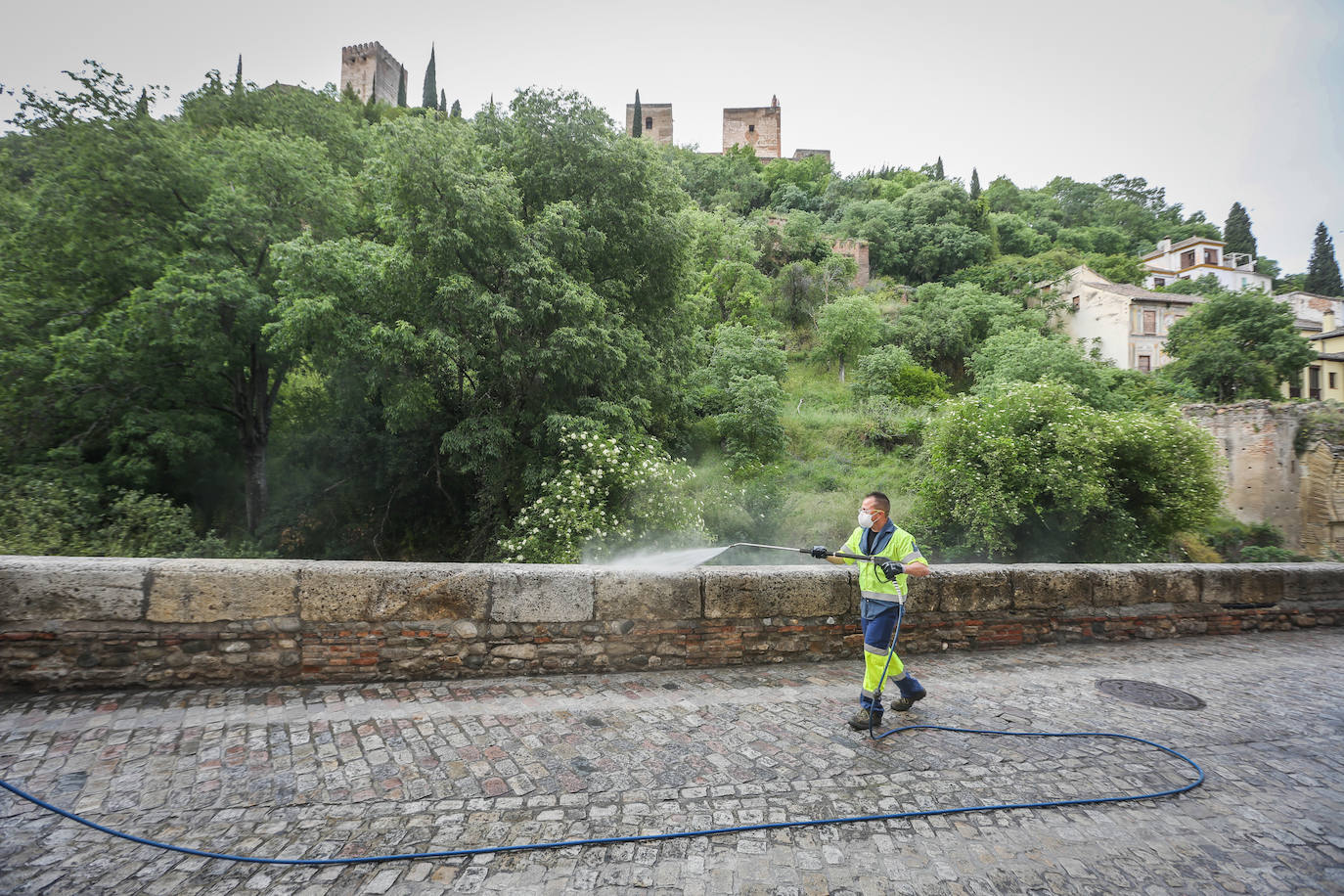 Operarios de Inagra desinfectan el Paseo de los Tristes, con la Alhambra como telón de fondo.
