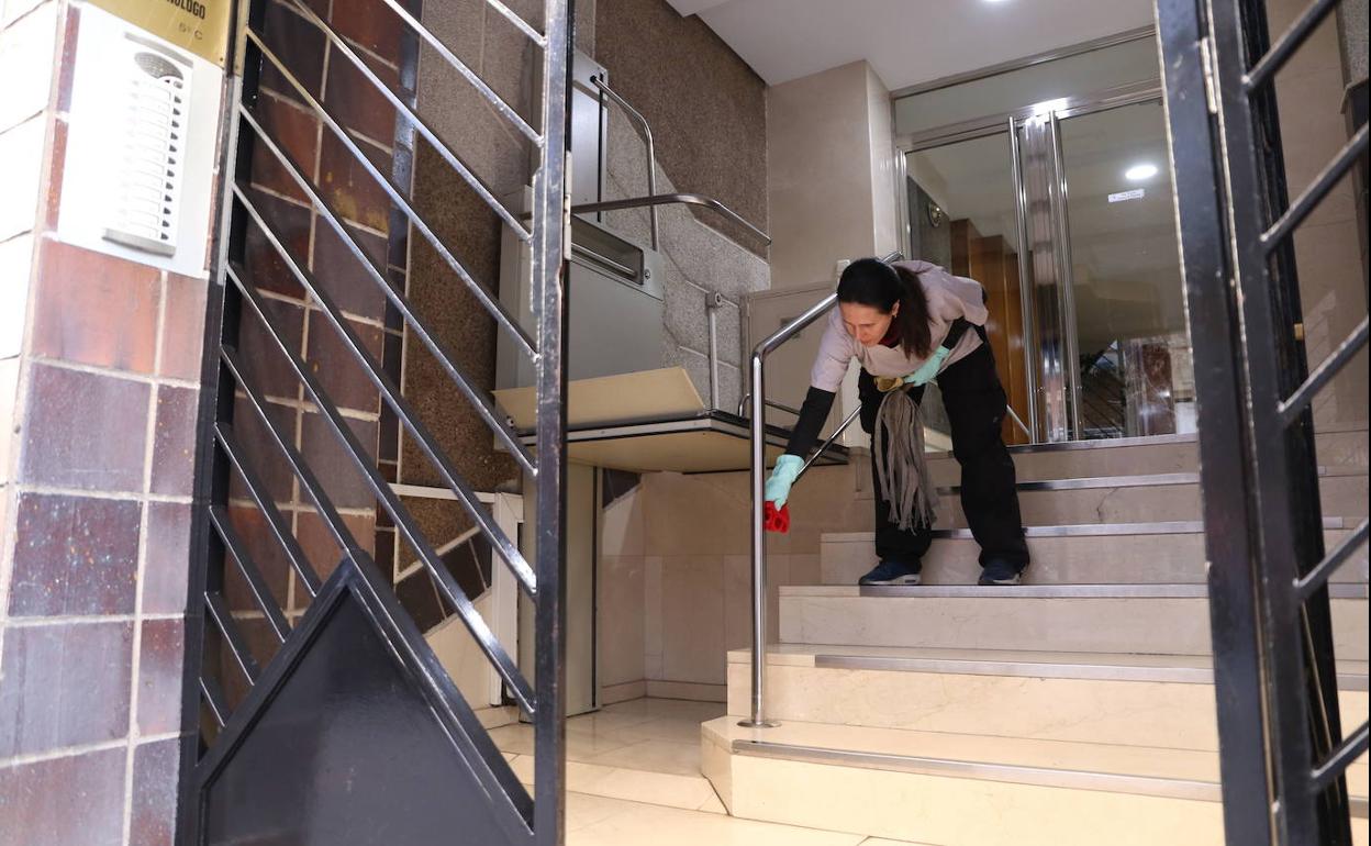 Una trabajadora limpiea una escalera.