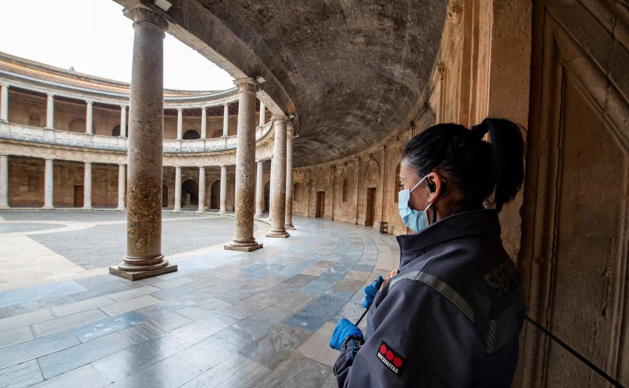 Un miembro de seguridad contempla el palacio de Carlos V de la Alhambra en Granada este sábado