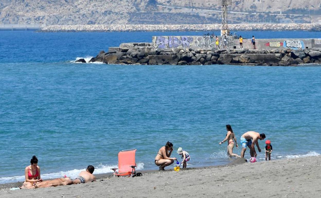 Varias familias disfrutan de la playa en Nueva Almería, junto al espigón de La Térmica. 