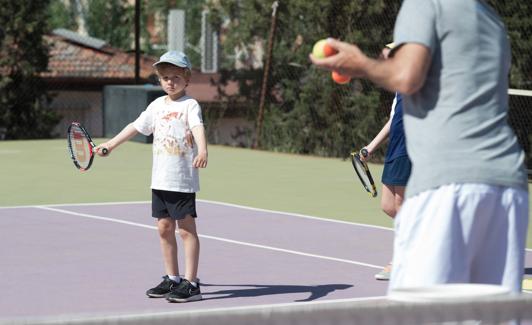 Un miembro de la escuela de tenis de la Real Sociedad practica junto a su monitor y compañeros. 