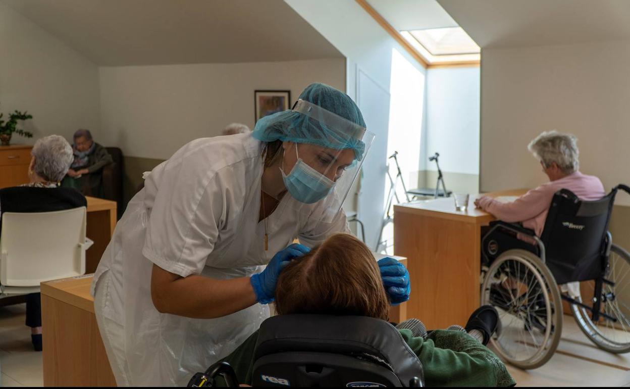 Una trabajadora atiende a los ancianos de una residencia