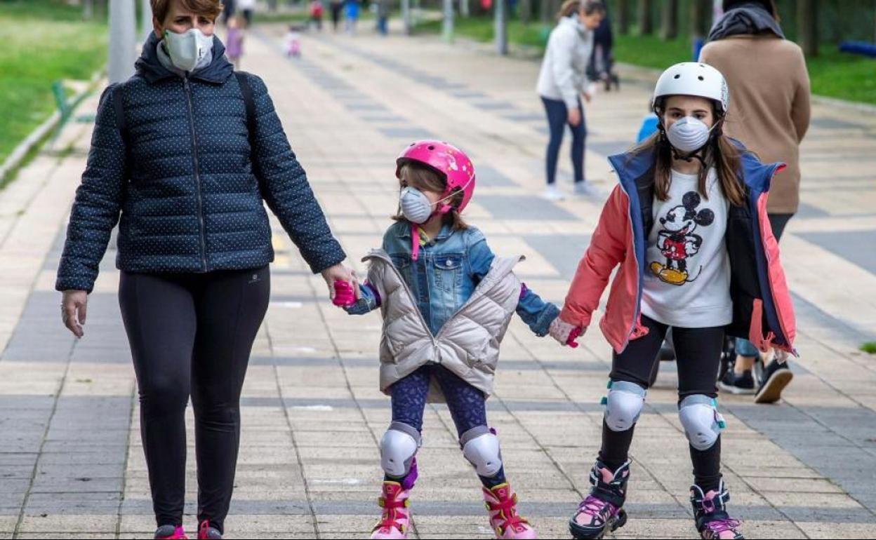 Niños y padres paseando en la calle con mascarilla durante el brote de coronavirus. 