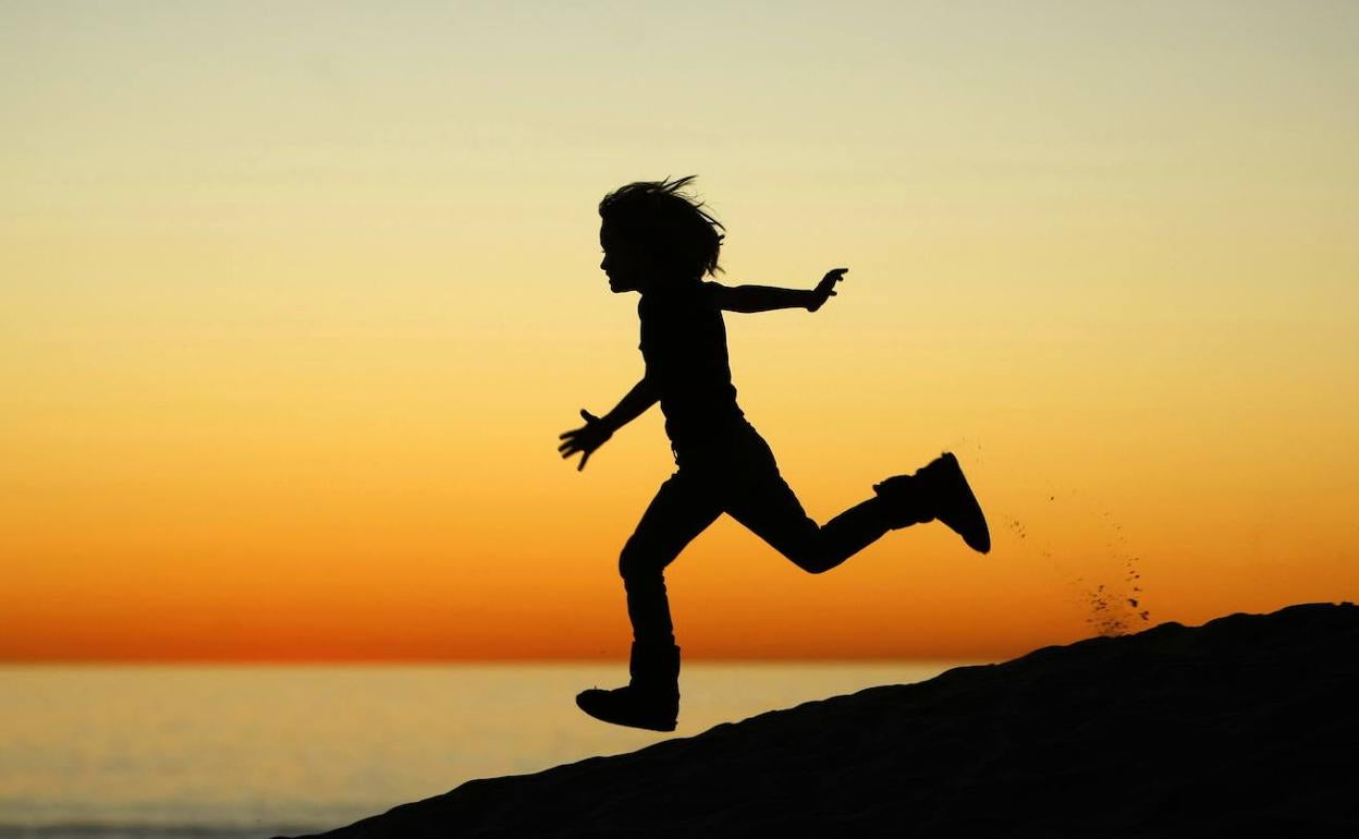 Un niño corre por una playa,