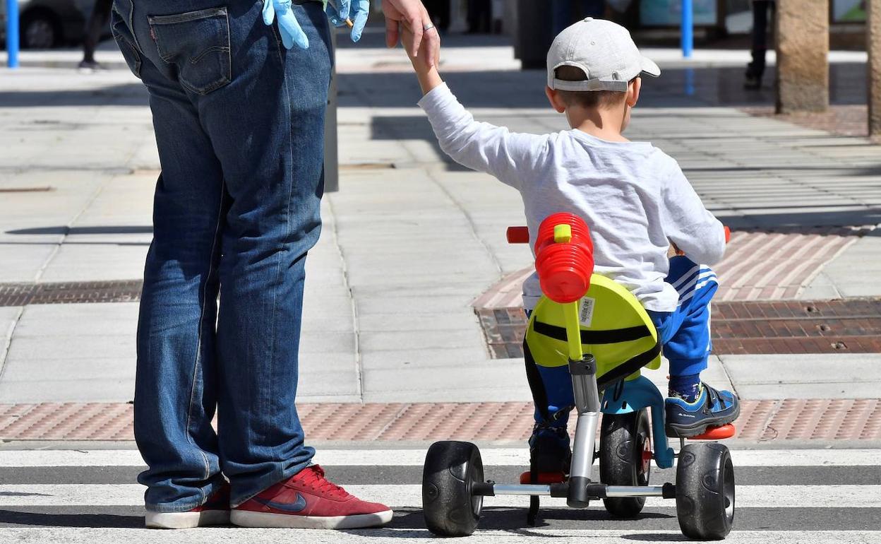 Un menor, en triciclo, pasea con su padre por el centro de Almería. 