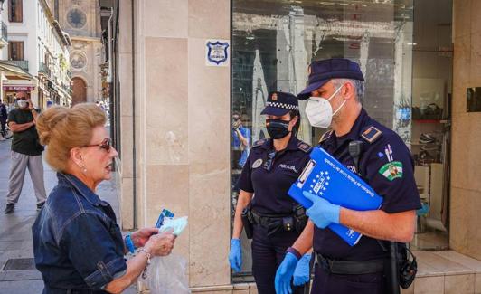 Dos policías locales informan a una mujer sobre el uso de mascarilla en mayo, cuando la norma era menos estricta.