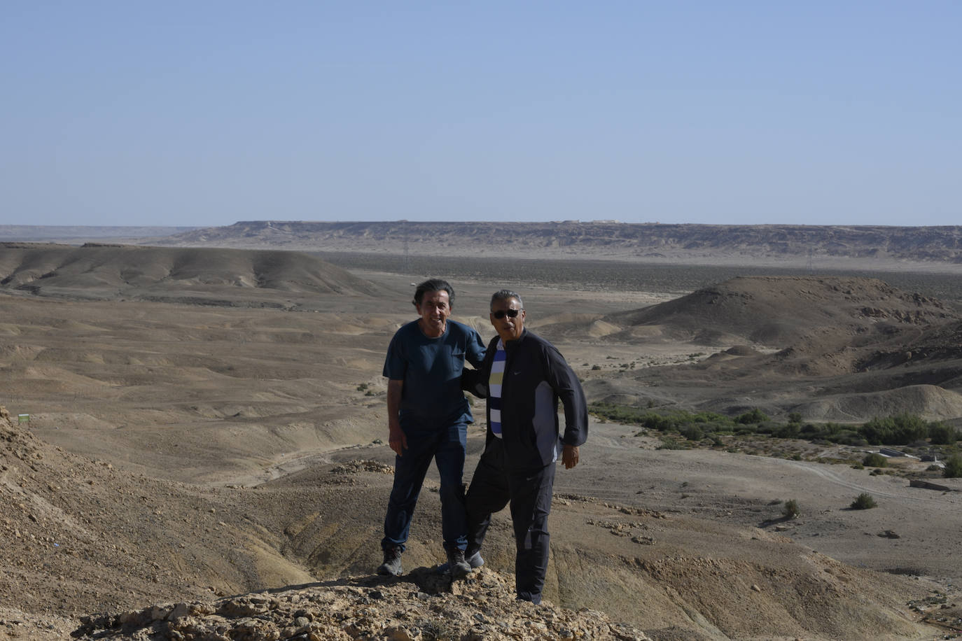 Rafael Hoces, en su viaje, con un antiguo alumno visitando el desierto con el río Saguia el-Hamra al fondo y dándoles el siroco. 