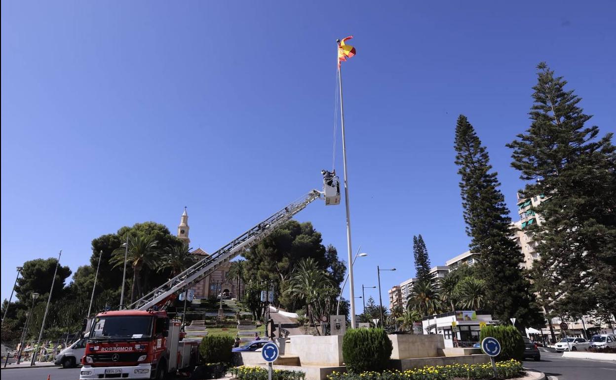 Los bomberos colocando la bandera en la rotonda.