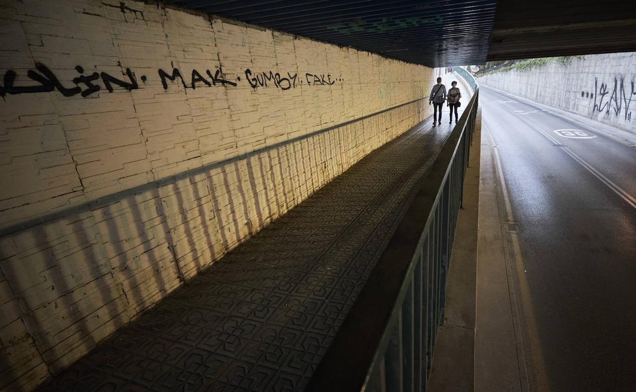 Estrecha y mal iluminada. Así es la acera por la que se accede al barrio.