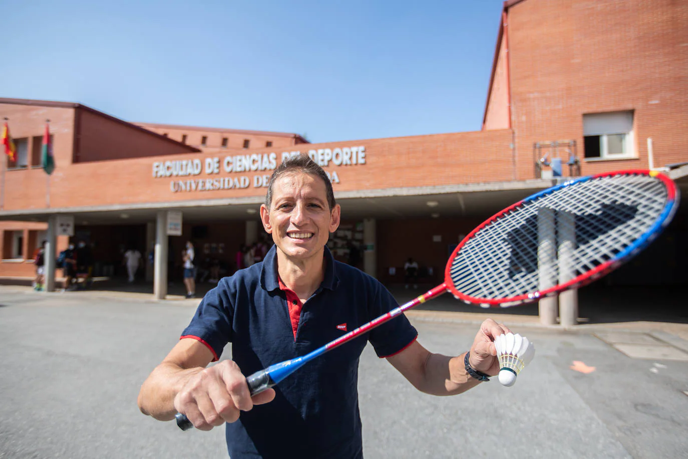 David Cabello posa con una raqueta de bádminton y un volante en la Facultad de Ciencias del Deporte. 