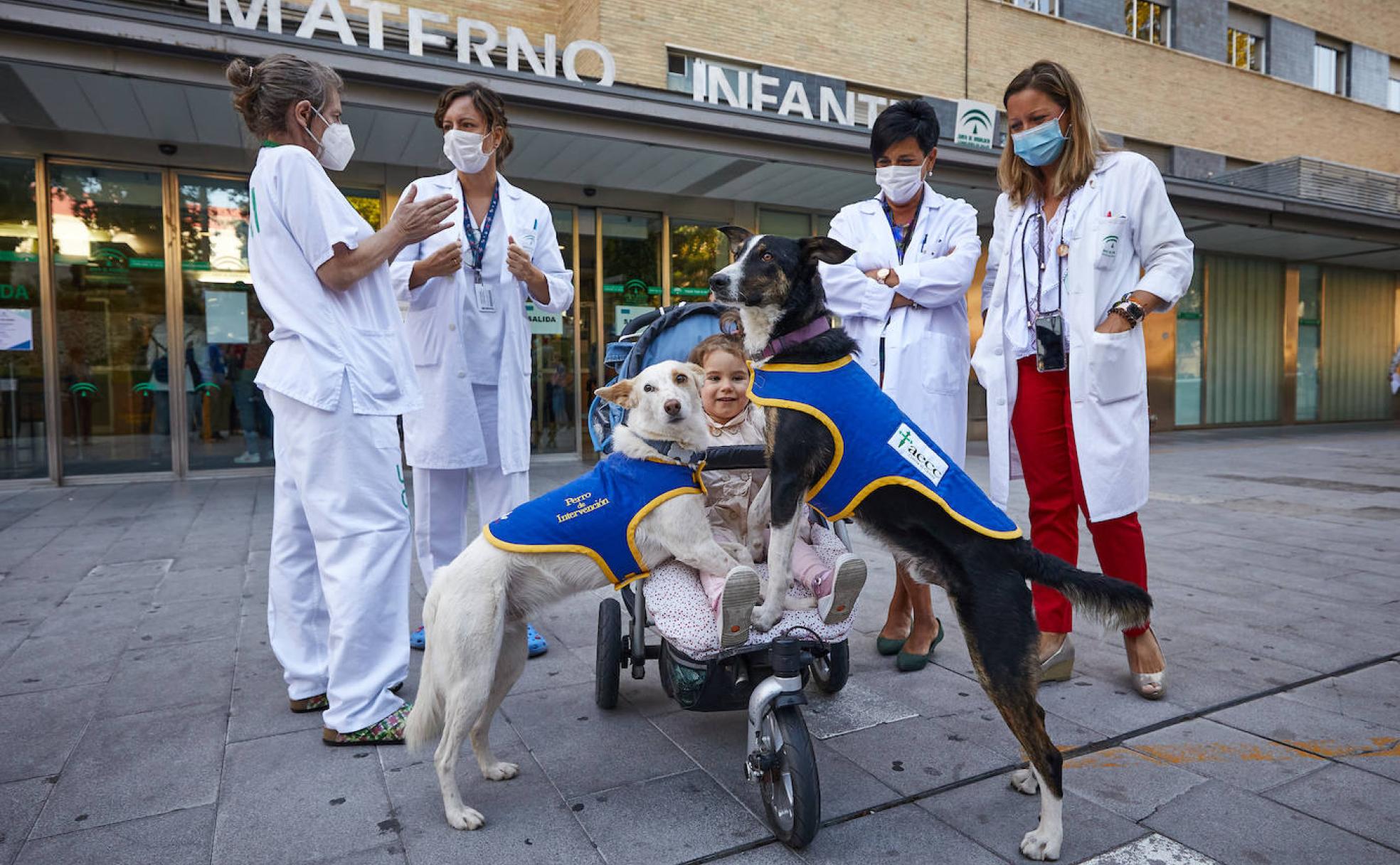 Pecas (izda) y Rufino juegan con una niña en el Materno ante la mirada de las sanitarias de la unidad.