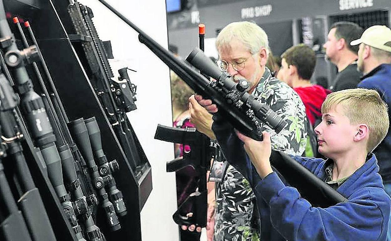 Un padre y su hijo examinan unas armas en una feria en Estados Unidos.