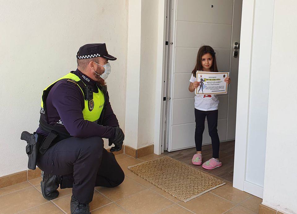 El jefe de la Policía Local de Íllora, Antonio Cobos, entrega un diploma a una pequeña en los meses de confinamiento. 