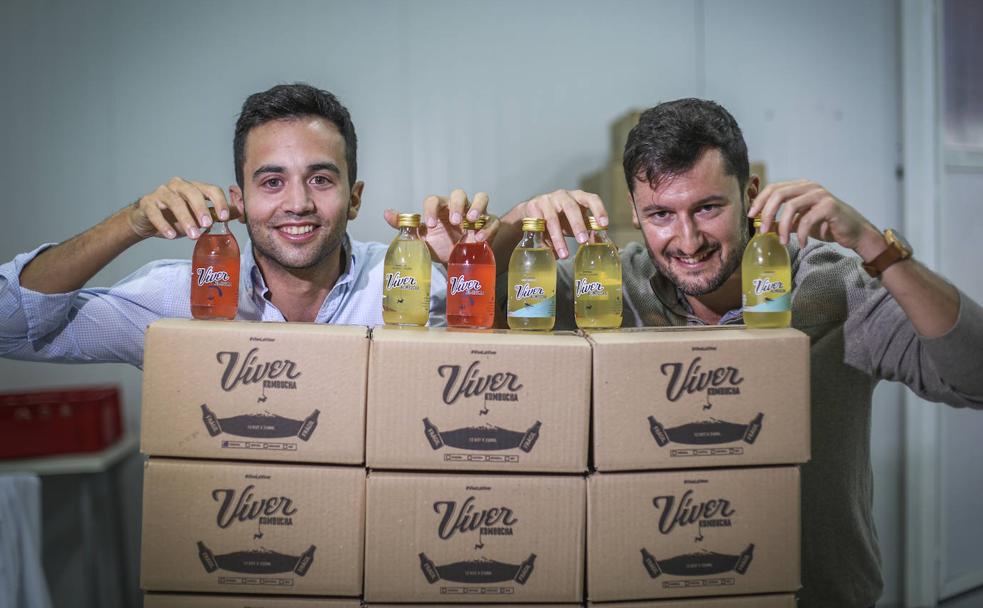 Fernando Martín y Raúl de Frutos posan con cajas y botellas de su refresco, la Víver Kombucha.