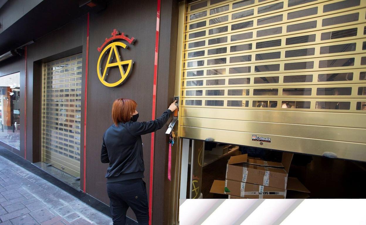 Una mujer abre la persiana de su negocio en la localidad granadina de Motril. 