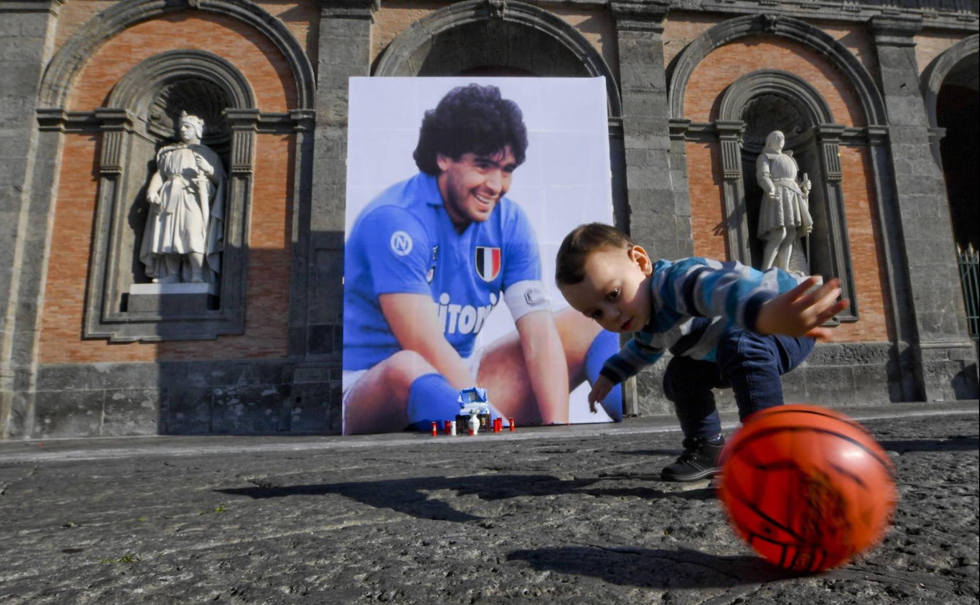 Un niño juega con una pelota delante de un recuerdo improvisado a Maradona tras su muerte en Nápoles. 