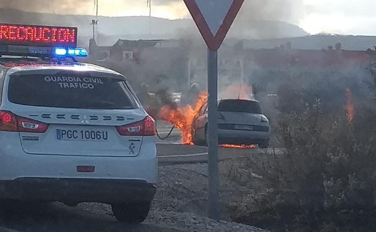 Bomberos sofocan las llamas del vehículo incendiado en la rotonda de la salida 144 de la Autovía de la Costa Tropical.