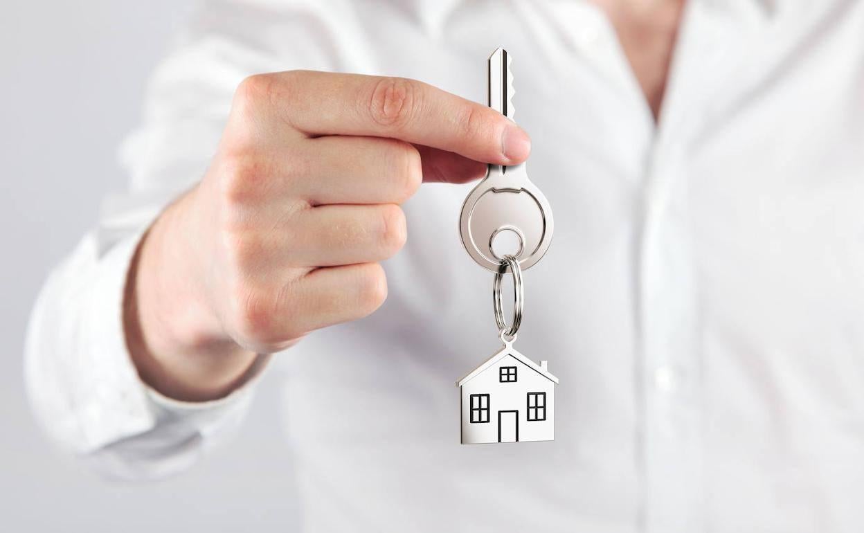 Un hombre entrega las llaves de una casa nueva. 