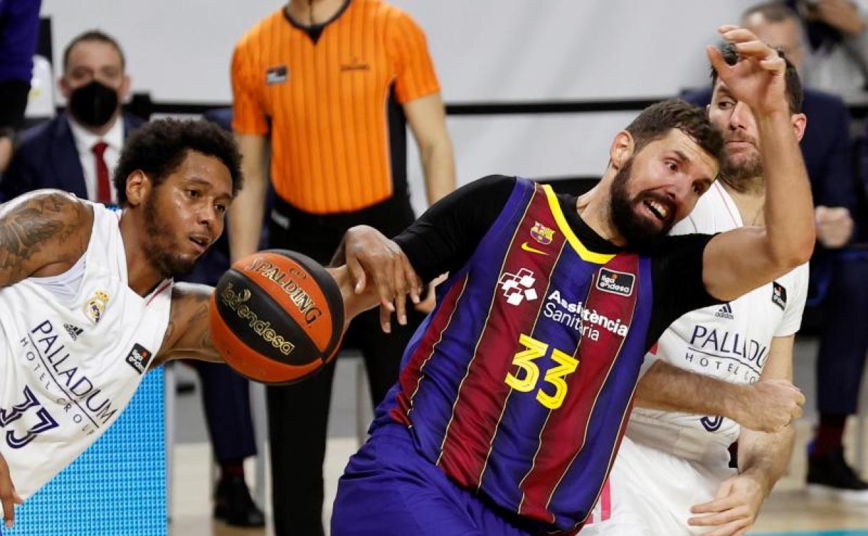 El ala pívot del Real Madrid Trey Thompkins lucha con Nikola Mirotic, del Barça.