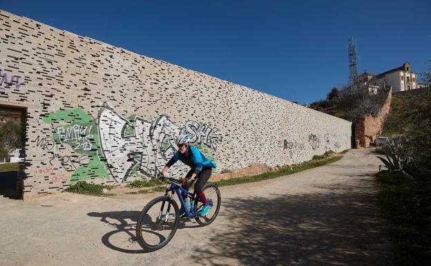 Un ciclista desciende junto al tramo del muro restaurado por Torrecillas.