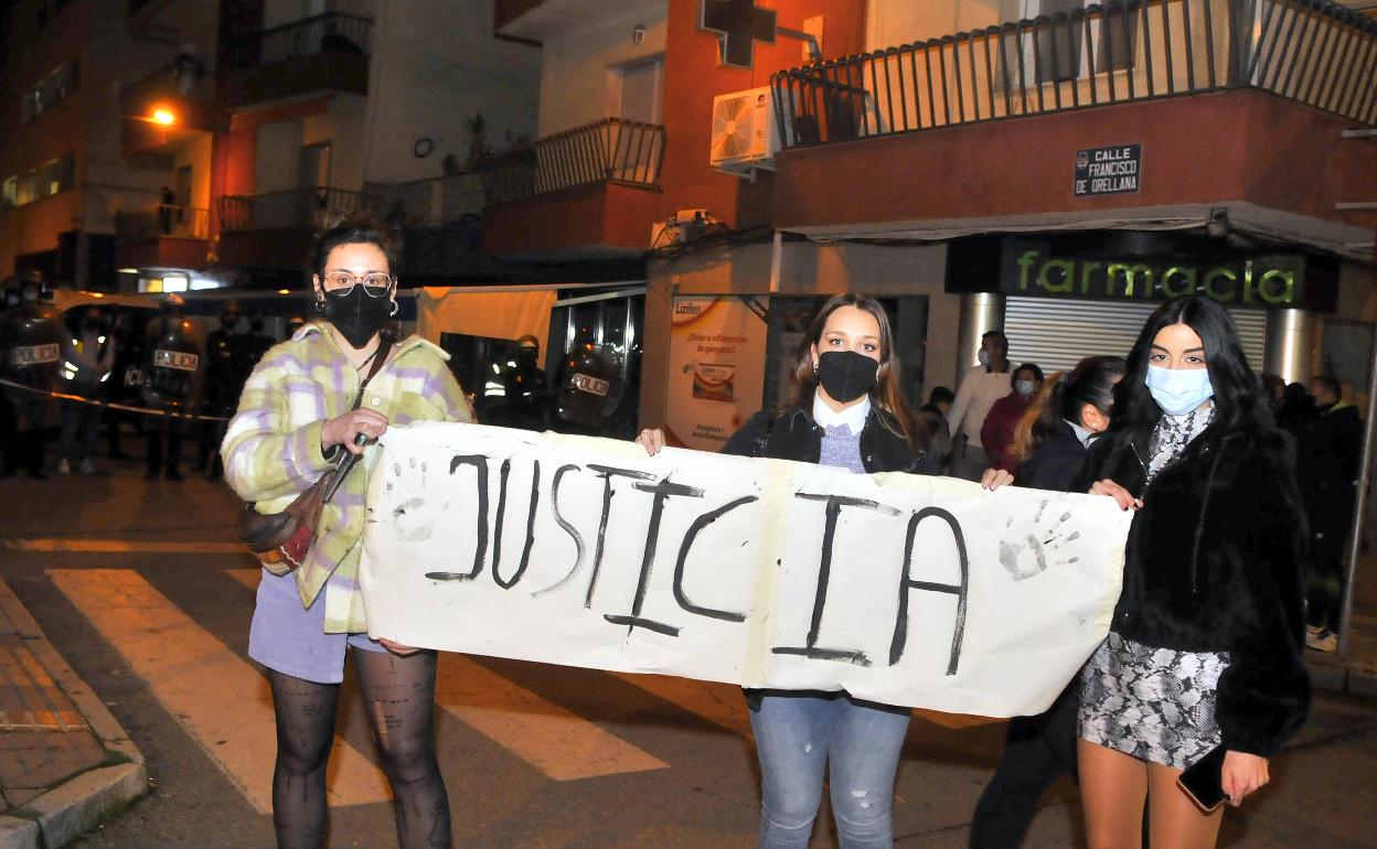 Jóvenes piden justicia tras la agresión, con el cordón policial al fondo para proteger la Comisaría.