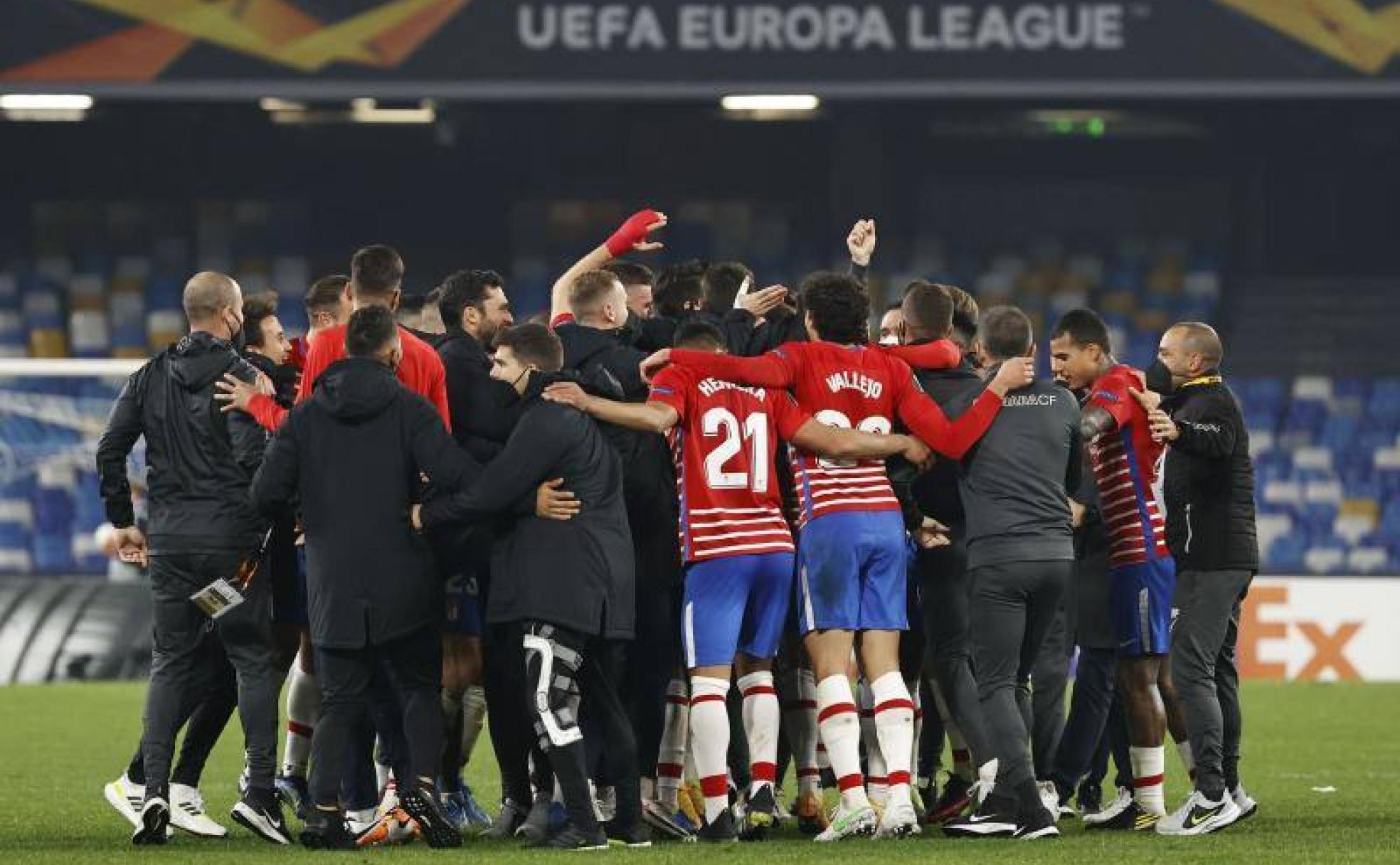 Jugadores y técnicos del Granada en Nápoles celebran como una piña el pase a octavos sobre el césped del estadio Diego Armando Maradona.