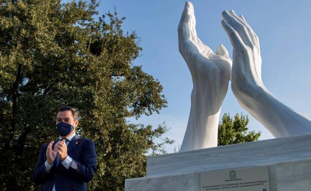 El presidente de la Junta junto a la escultura a los sanitarios. 