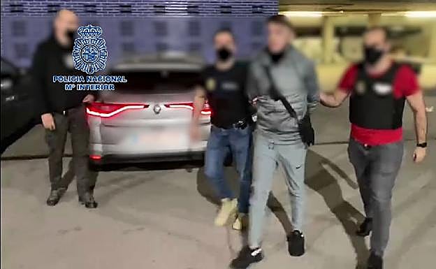 El detenido, custodiado por dos agentes de policía. 