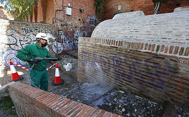 Un operario limpia las pintadas del aljibe.