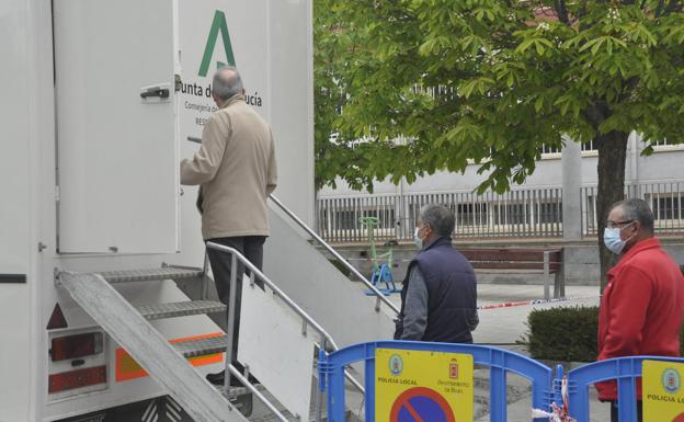 Vecinos esperan su turno en la unidad móvil, en Baza. 