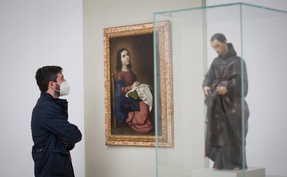 Un visitante observa con atención el cuadro 'Virgen niña rezando' del pintor Francisco de Zurbarán. En el primer plano, San Diego de Alcalá, una escultura de Alonso Cano.. 