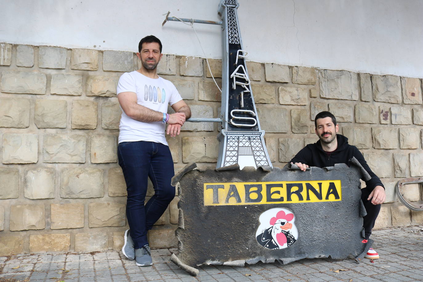 Juan y Carlos posan con un letrero de la Taberna París