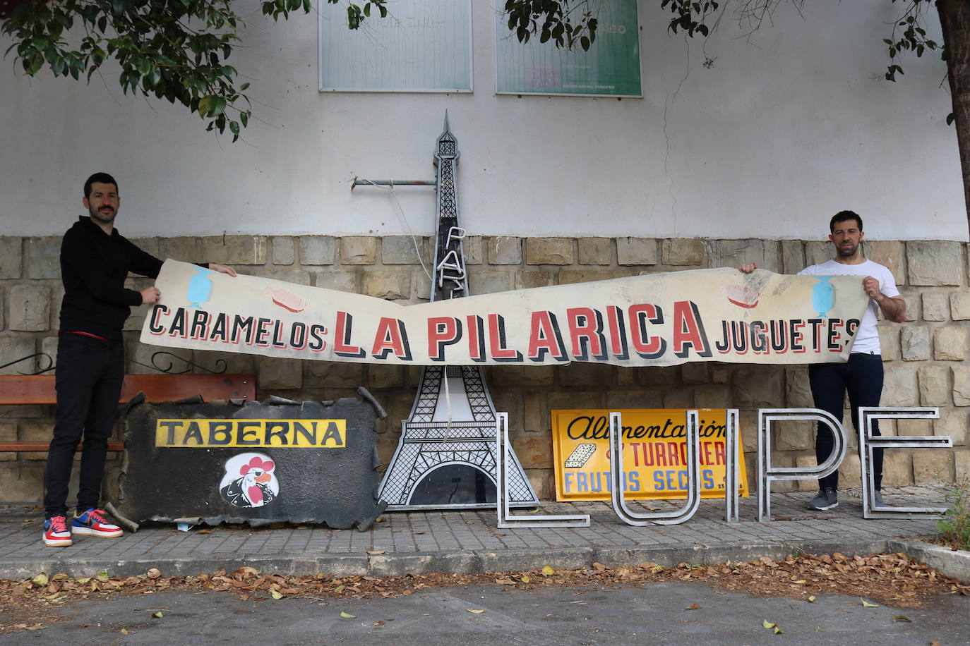 Juan y Carlos posan con un letrero de la Taberna París