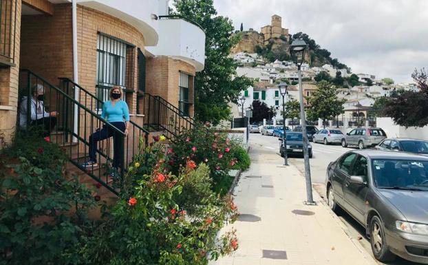 Imagen principal - Maria y Ana, vecinas de la calle Zanjón, confinadas este domingo en casa. La plaza de la iglesia prácticametnte vacía y en la última imagen el presidente de los comerciantes (derecha) charlando en su negocio con otro comerciantes. 