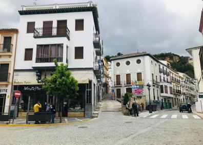 Imagen secundaria 1 - Maria y Ana, vecinas de la calle Zanjón, confinadas este domingo en casa. La plaza de la iglesia prácticametnte vacía y en la última imagen el presidente de los comerciantes (derecha) charlando en su negocio con otro comerciantes. 