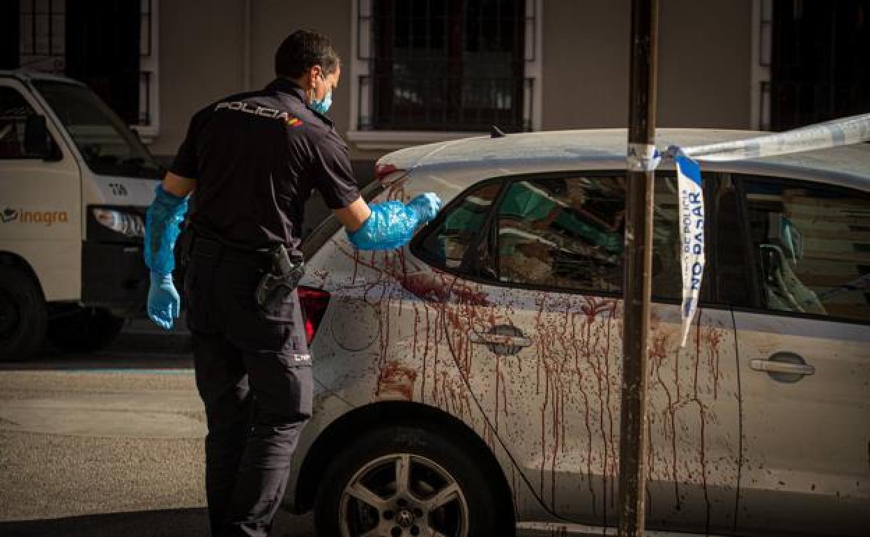Un policía nacional recoge restos de sangre de uno de los vehículos tras la reyerta de la madrugada del miércoles.